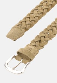 Ljusbrun flätad mockabält med en silvermetallspänne. Har en slät yta och spetsiga ändar. Enkel och funktionell design utan mönster.