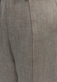 Κοντινή λήψη γκρι και καφέ ύφασμα tweed με ορατή ραφή και υφασμένο υφή.