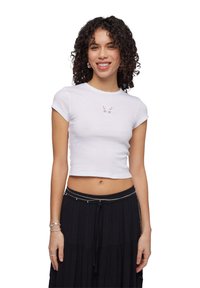 T-shirt bianco corto realizzato in tessuto a costine con un design a farfalla al centro. Maniche corte e scollo rotondo.