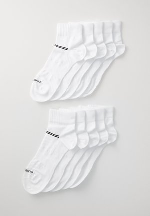 Fehér pamut zoknik két sorba rendezve, a tetején fekete csíkkal, bordázott szárakkal és az oldalukon logóval.