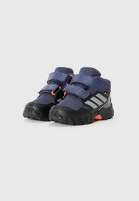 Chaussures de randonnée de couleur marine avec semelles noires, dessus texturé, sangles Velcro et accents gris. Caractéristiques d'un orteil renforcé et détails en orange vif.