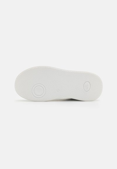 Semelle de sneaker blanche avec une surface texturée, présentant des motifs de grip circulaires et deux accents circulaires près du centre.