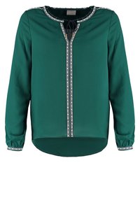 Långärmad tealblus med vit och svart mönstrad kant vid halsringning, front och ärmslut, med en liten rosett vid halsen.