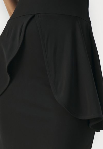 Musta peplum-mekko, jossa on istuva yläosa ja virtaava, laskostettu alaosa. Sileä pinta ja siistit saumat korostavat muotoilua.