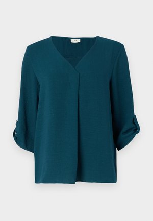 Tirkizna bluza z odprtim V-izrezom, s tridelnimi rokavi in gumbi na manšetu. Narejena iz teksturirane tkanine, ohlapnega kroja in z detajlom zgornje gube.