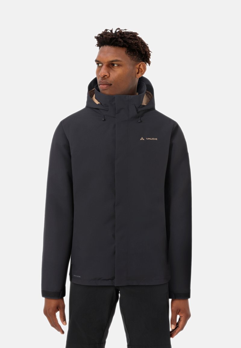 Schwarz wasserfeste Jacke mit Kapuze, ausgestattet mit einem Reißverschluss vorne, elastischen Bündchen und einem beigen Innenfutter. Markenlogo auf der Brust sichtbar.