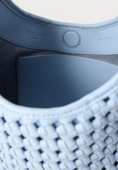 Εσωτερικό τσάντας από μπλε δέρμα με ραμμένο κουμπί πατιλέτας, εξωτερική λεπτομέρεια πλεγμένη, ανάγλυφες επιγραφές "Elleme Paris" και "Made in Italy".