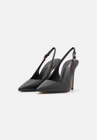 Escarpins noirs en cuir avec bride arrière, à bouts pointus, talons fins et détail de boucle en or. Finition lisse et design épuré.