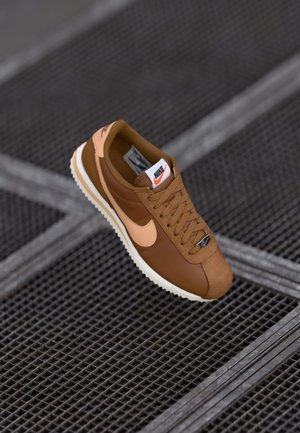 Baskets marron avec des accents beiges, en cuir et en suède, bout rond, semelle texturée et logo Nike bien visible sur la languette.