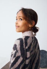 Sweater featuring a fuzzy texture with a pink base and bold black tiger stripes. High collar design, lightweight, and cozy appearance.