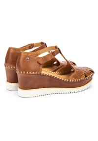 Sandali wedge in pelle marrone con design perforato, due cinturini regolabili e suola in gomma bianca a contrasto. Presentano cuciture decorative.