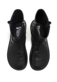 Botas de tobillo de cuero negro con textura lisa, que cuentan con un cierre de cremallera lateral y un diseño minimalista. Interior forrado con suelas planas.