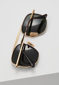 Black square sunglasses with gold metal accents and tortoiseshell temple arms. Features a double bridge and adjustable nose pads.