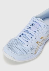 Lichtblauwe sportschoen met bovenwerk van mesh, textuurdetails, gouden accenten en een traditioneel vetersysteem. Solide witte zool.