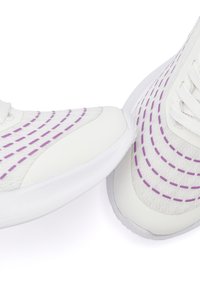 Weiße Sneakers aus strukturiertem Material mit lila gestrichelten Linien und einer festen weißen Sohle. Schnürdesign mit abgerundetem Zehenbereich und Nähdetails.