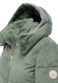 Quilted grønn jakke med en teksturert overflate, høy krage og hette. Har glidelås foran og et rundt logo-patch på ermet.