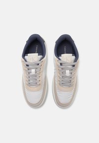 Calvin Klein sneakers in white, beige, and navy. Smooth leather and textile upper, round toe, padded collar, and flat laces.