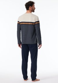 Herren Langarmshirt mit Streifen in Beige, Marineblau und Braun, kombiniert mit Marineblauen Hosen. Aus Baumwolle, mit lockerer Passform und schlichtem Design.