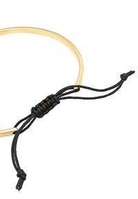 Gouden metalen choker met een gladde, ronde vorm; heeft een zwart gevlochten koord dat in het midden is gestrikt met kwastjes.