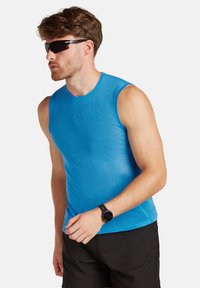 Blaues ärmelloses Sporthemd mit strukturiertem Stoff, runder Ausschnitt, kombiniert mit schwarzen Shorts und Sonnenbrille, getragen mit einer Armbanduhr.