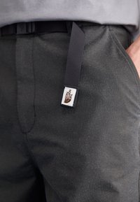 Grau Wanderhosen aus strukturiertem Stoff, ausgestattet mit einem schwarzen verstellbaren Riemen und einem beschrifteten Aufnäher mit Logo am Bund.