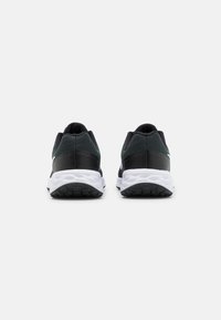 Zapatillas deportivas de malla en negro y verde oscuro con contra talón sintético, entresuela blanca y suela texturizada negra.
