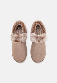 Chaussons beiges avec une douce doublure en fausse fourrure et un col. La tige est en tissu texturé, dotée d'une semelle intérieure rembourrée et d'une semelle plate.