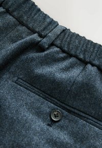 Wool blend trousers in dark blue with elastic waistband, flat front, back pocket, and black button detail. Soft texture and tailored design.