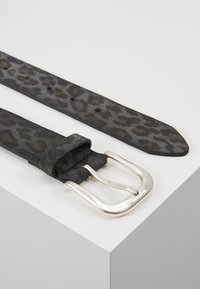 Black leather belt featuring a leopard print pattern, silver metal buckle, and multiple adjustment holes along the strap.