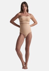 Body senza maniche beige con texture liscia, design a vita alta e sottile fascia elastica. Presenta una parte superiore aderente con dettagli cuciti.