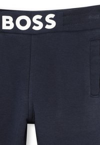Pantaloni sportivi blu navy con texture a coste, caratterizzati da un logo bianco "BOSS" sulla cintura elastica e un dettaglio con tasche laterali.