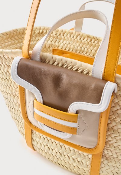 Πλεκτή τσάντα ώμου από άχυρο με λουριά μουσταρδί και μπροστινή τσέπη που διαθέτει καφέ, μπεζ, λευκές και κίτρινες δερμάτινες λεπτομέρειες.
