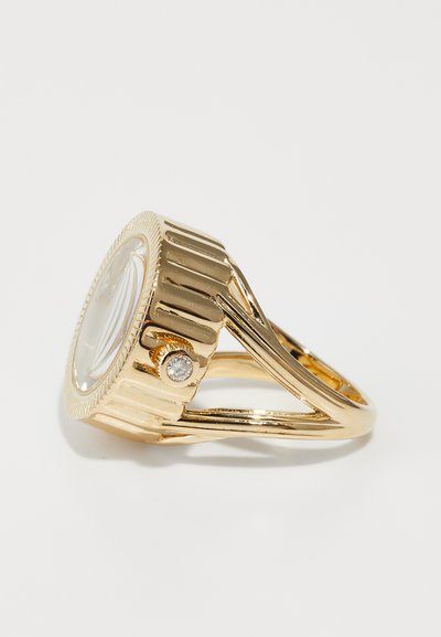 Goldplattierter Ring mit einem geriffelten Band, einem klaren ovalen Stein und einem kleinen runden Diamant-Akzent in der Nähe der Fassung. Glatte Oberfläche und poliertes Finish.