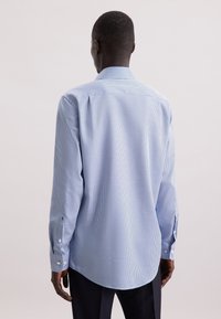 Camicia a maniche lunghe con motivo a quadretti blu e bianchi, realizzata in tessuto leggero. Presenta un colletto a punta e polsini con bottoni.