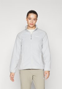 Giacca in pile grigio chiaro con collo alto, zip intera e due tasche laterali. Presenta una texture liscia e un discreto dettaglio del logo sul petto.