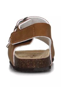 Sandal brown con suola piatta in sughero, cinturino regolabile con dettaglio fibbia e cuciture bianche in evidenza. Design open-back. Texture liscia.