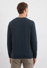 Dunkelblaues Langarmshirt mit Rundhalsausschnitt, gerippten Bündchen und Saum. Glatte Textur, schlichtes Design und keine sichtbaren Muster oder Grafiken.