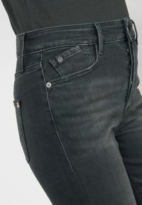 Mörkgrå denimjeans med en klassisk passform, fem fickor och subtila sömdetaljer. Tyget har en jämn, något texturerad yta.
