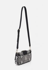 Bolso de mano con estampado de serpiente en blanco y negro, con una solapa negra sólida y tachuelas doradas. Cuenta con una correa de hombro negra ajustable.