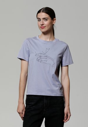 T-shirt en coton violet clair présentant un dessin linéaire minimaliste noir de deux mains tenant une feuille. Manches courtes et col rond.
