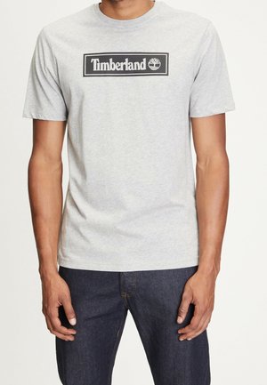 Grå bomulds T-shirt med rund halsudskæring med en sort rektangulær Timberland-logo trykt foran. Korte ærmer, afslappet pasform.