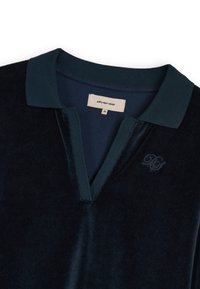 Granatowa polo z welwetu z ciemnozielonym prążkowanym kołnierzykiem, haftowanym logo po lewej stronie klatki piersiowej oraz trzema guzikami. Rozmiar M.