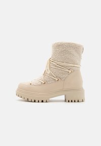 Beżowy botek za kostkę z górną częścią z polaru, dolną ze skóry gładkiej, złotym okuciem, okrągłym noskiem i teksturowaną gumową podeszwą z bieżnikiem typu lug.
