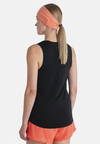 Top negro sin mangas, fabricado en un material ligero; combinado con una diadema naranja. El cabello está peinado en una coleta; diseño sencillo sin adornos.