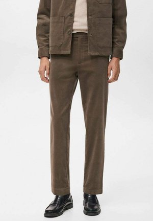 Pantalones de pana marrones con corte recto, presentan un cierre de botón y bolsillos laterales, combinados con zapatos de cuero negros.