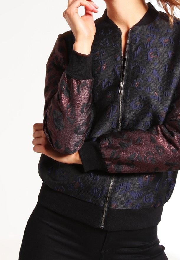 Bomberjacka med ett strukturerat mönster i svart och bordeaux, med dragkedja framtill och svarta ribbade muddar. Tyget har en subtil glans.