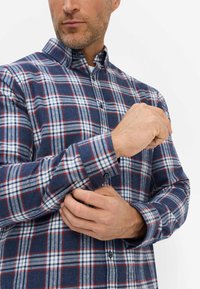 Hemd mit Knopfleiste in Marineblau, Rot und Weiß im Karomuster. Aus Flanell gefertigt, mit einem Kragen und langen Ärmeln mit Knopfmanschetten.