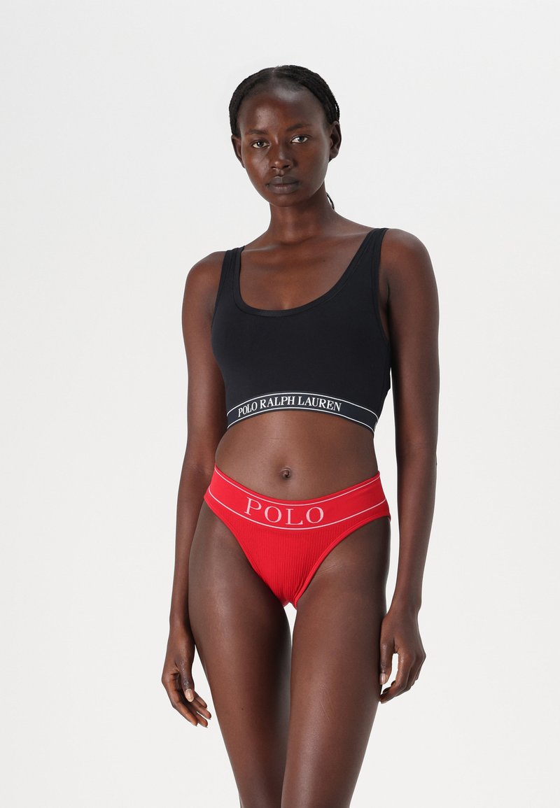 Μαύρο αθλητικό σουτιέν με λογότυπο στη ζώνη, συνδυασμένο με κόκκινες ριγέ μπραζίλ με λογότυπο στη ζώνη.