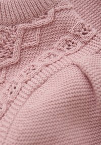 Stickad tröja i ljusrosa, med intrikata detaljer med texturerade stygn och en ribbad krage. Mjuk och mysig tyg.