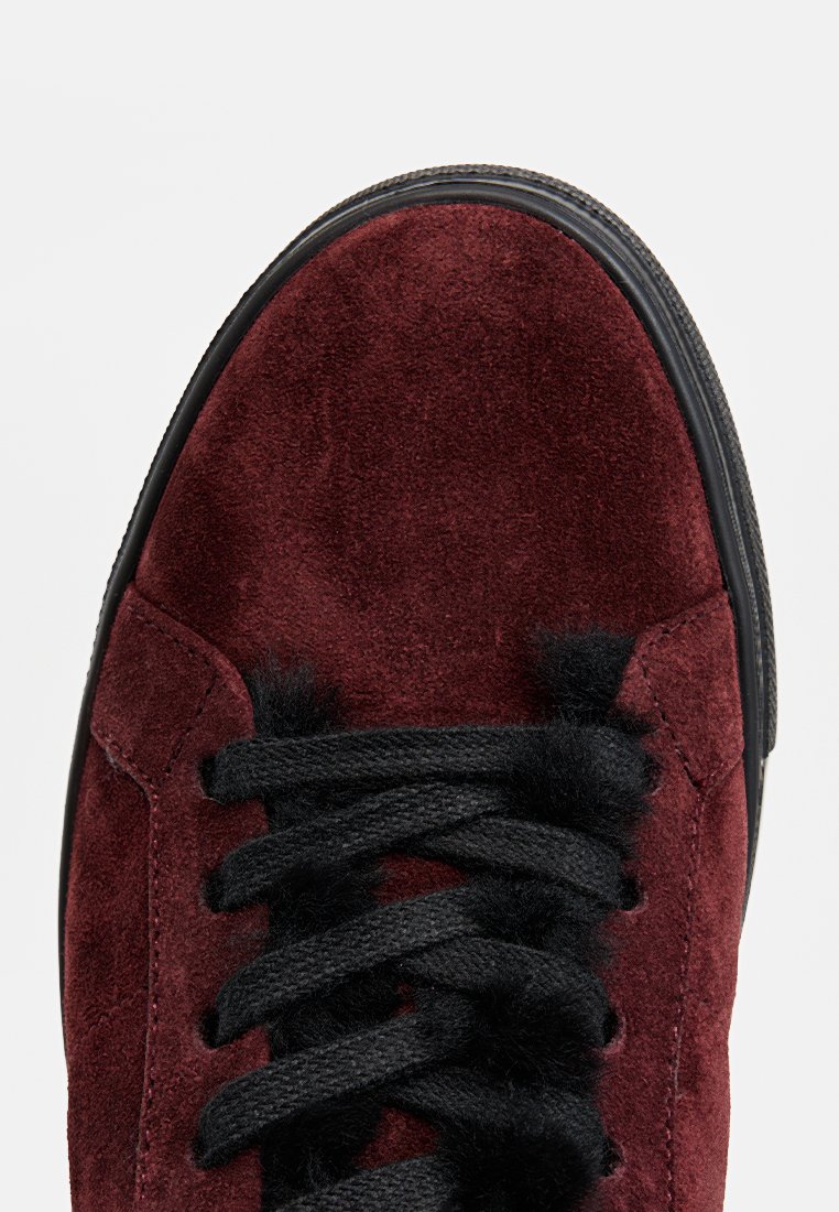 Bordowe zamszowe sneakersy z okrągłym noskiem, czarnymi sznurowadłami i teksturowaną powierzchnią. Posiadają kontrastującą czarną gumową podeszwę.